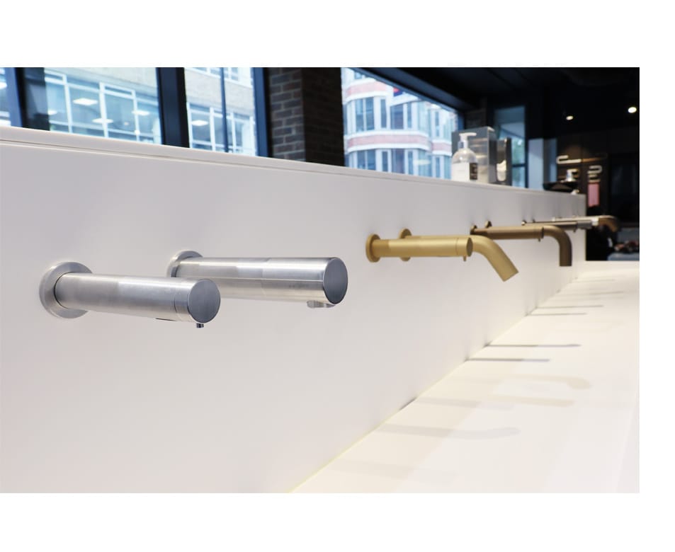 Row of special finished touch free taps and soap dispensers equipped with SMART technology for commercial washrooms