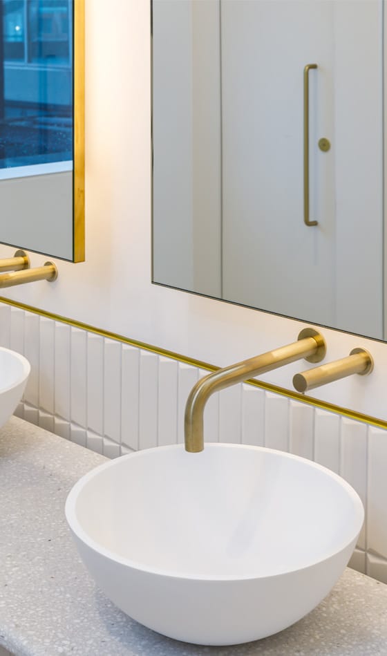 Dolphin touch-free tap in gold finish with circular countertop basin