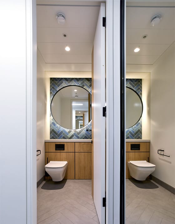 Side-by-side toilet cubicles using a wall-hung WC pan