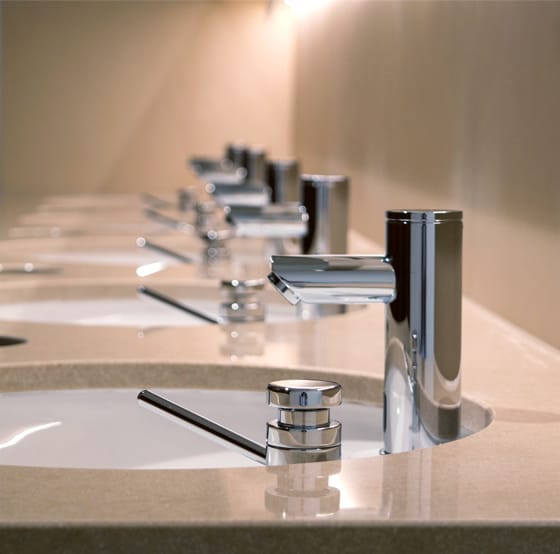 Counter top row of mirror polish stainless steel touch free taps and manual soap dispensers