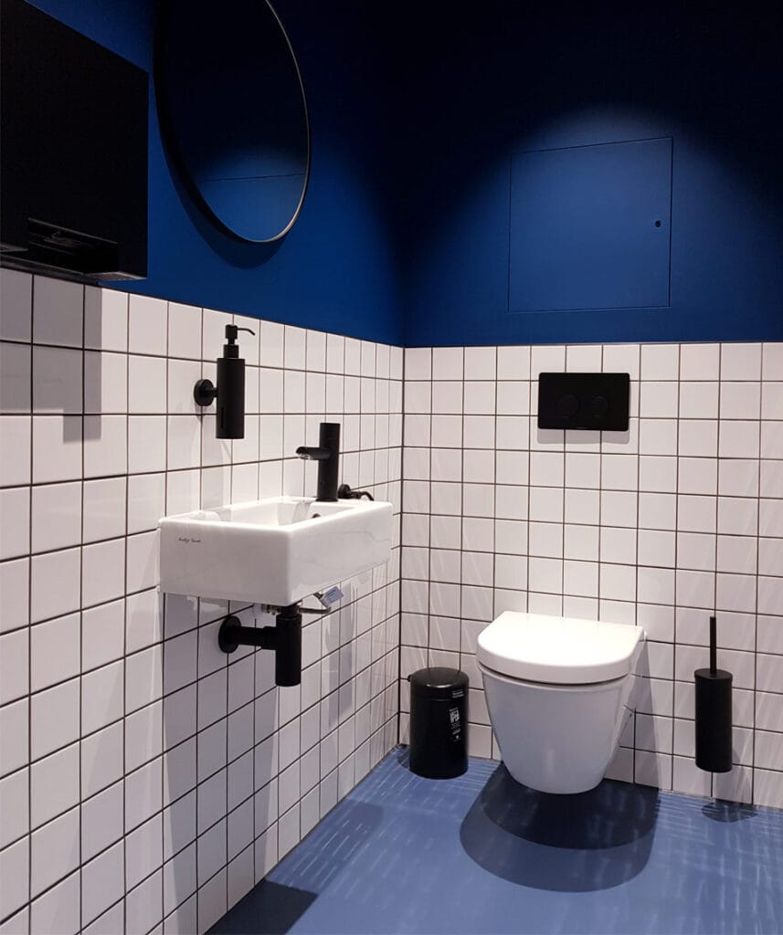 Wall-mounted toilet in a blue and black themed Superloo