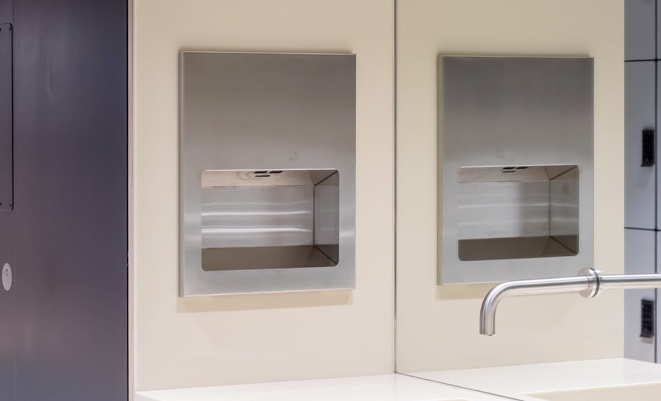 Recessed HEPA filter hand dryer and sensor tap reflected in a mirror
