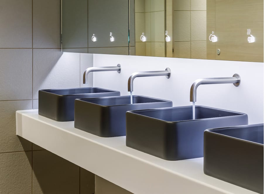 Row of commercial washroom sensor taps with two running water and one one is not working