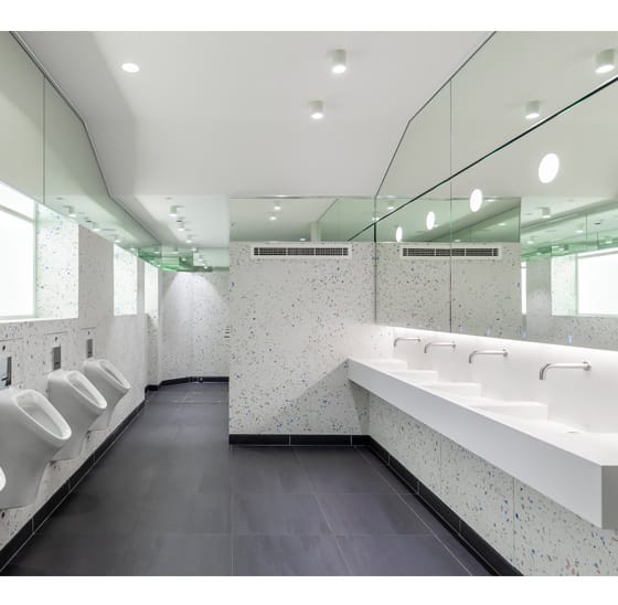 Large commercial men's washroom that has hot water on multiple taps