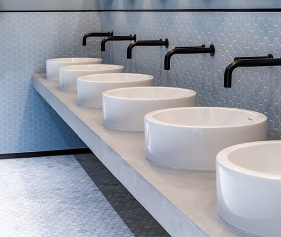 A row of circular countertop ceramic washbasins in glacier white