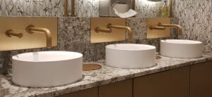 Automatic thru panel soap dispensers next to taps