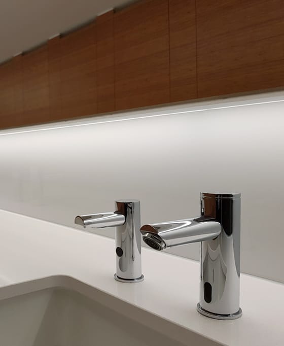 Sensor soap dispenser next to a commercial touch free tap