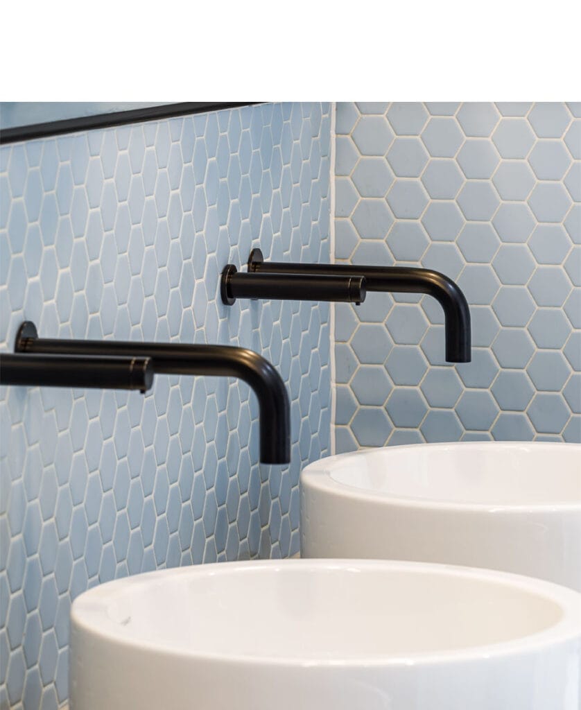 A line of black taps and soap dispensers installed with a wall plate