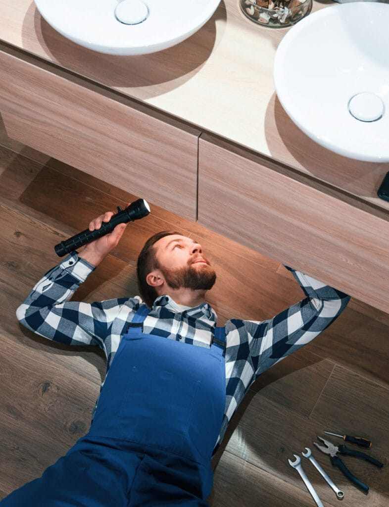 Man using under counter access panel for wall mounted tap maintenance