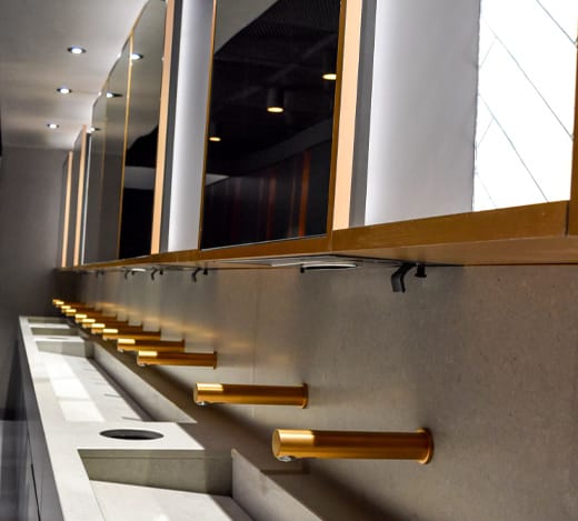 Row of gold finished taps under a behind mirror system