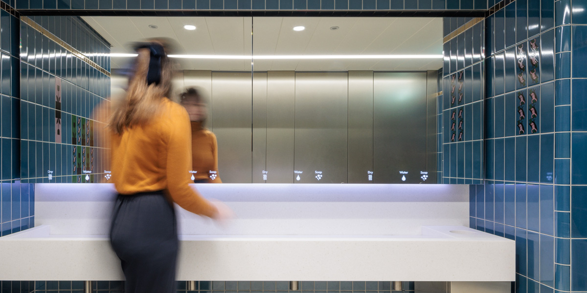 Woman in from of Alavo Behind Mirror System